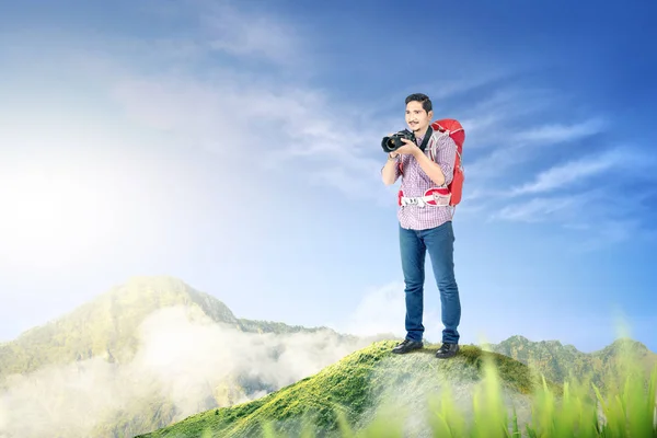 Asian man with a backpack holding a camera to take pictures — Stock Photo, Image