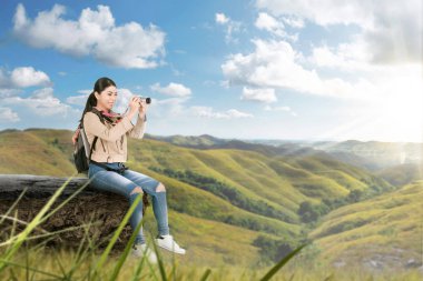 Kenar taş ve holdin oturan bir sırt çantası ile Asyalı kadın