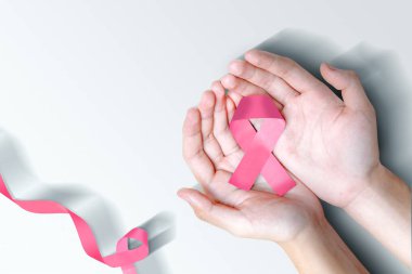 Pembe farkındalık kurdelesi gösteren insan elleri