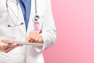 Pembe kurdeleli ve stet'li beyaz laboratuvar önlüğü giymiş bir kadın doktor.