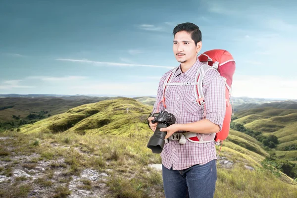 Азіатська людина з рюкзаком тримає камеру, щоб сфотографуватися — стокове фото