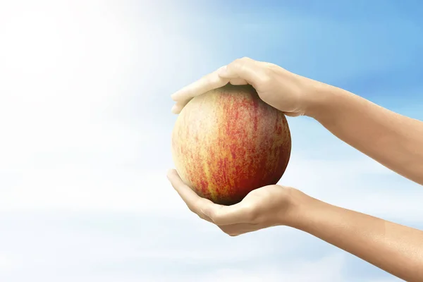 Human holding the apple fruit with a blue sky background — Stock Photo, Image