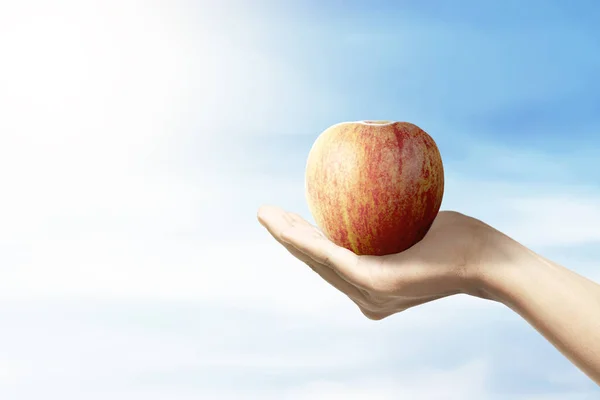 Human holding the apple fruit with a blue sky background — Stock Photo, Image