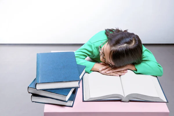 Asiatico carino ragazza con occhiali cadere addormentato su un libro su il scrivania — Foto Stock