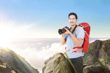 Fotoğraf çekmek için bir kamera tutan bir sırt çantası ile Asyalı adam