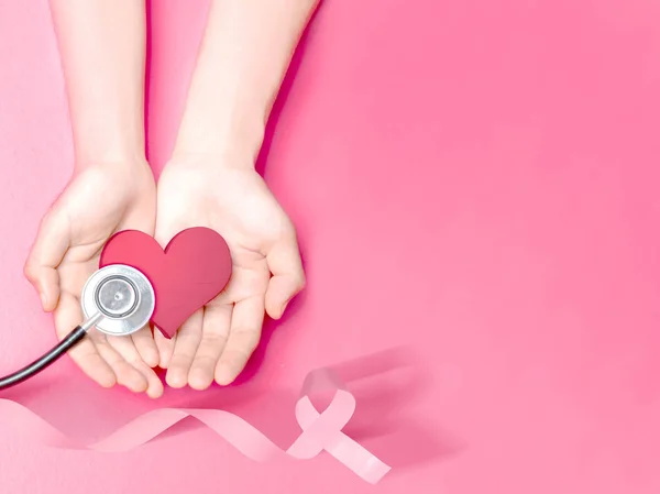 Mãos humanas mostrando um coração rosa e estetoscópio com uma costela rosa — Fotografia de Stock