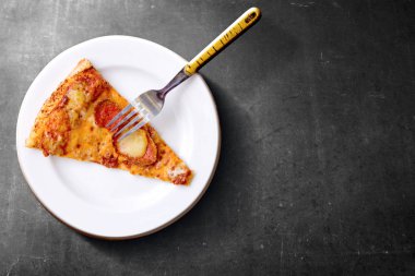 Siyah arka plan üzerinde çatal ile plaka üzerinde pizza Dilim