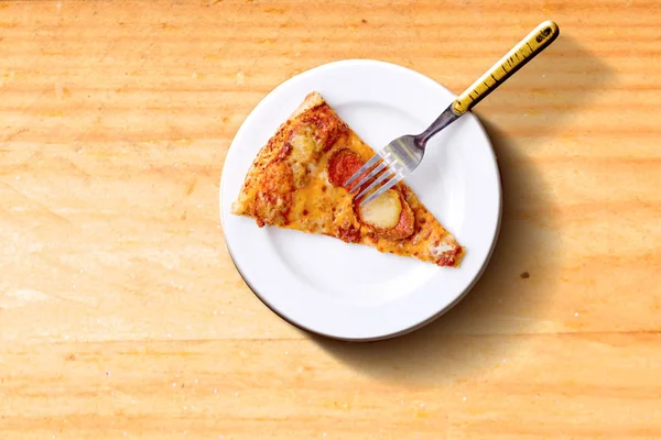 Stukje pizza op het bord met vork op houten tafel achtergrond — Stockfoto
