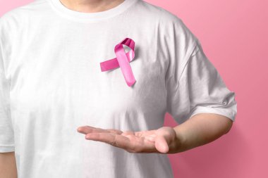 Pembe üzerinde pembe farkındalık kurdele gösteren beyaz gömlekli kadın