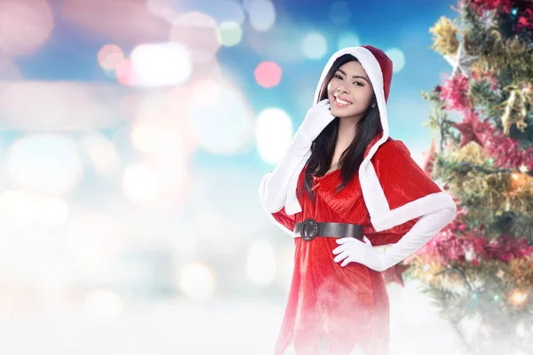 Noel Baba kostümü Asyalı kadın süslenmiş bir Noel ile ayakta — Stok fotoğraf