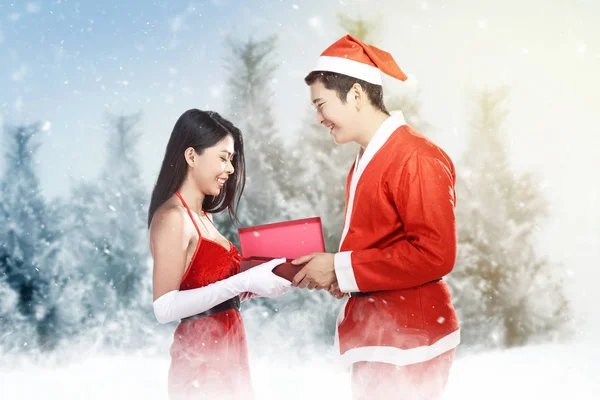 Asiatischer Mann im Weihnachtsmann-Kostüm gibt seiner Freundin eine Geschenkschachtel — Stockfoto