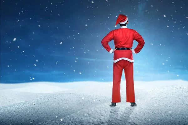 Noel Baba kostümü giymiş Asyalı bir adamın kar yağarken ayakta duruşu. — Stok fotoğraf