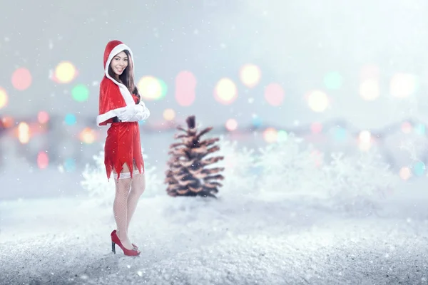Asiatin im Weihnachtsmannkostüm steht bei Schneefall — Stockfoto
