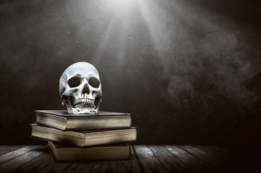 Tahta bir masanın üzerinde insan kafatası olan kitap yığını.
