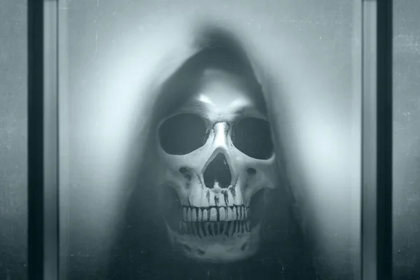 Human skull with a black cloak behind of window glass — 图库照片