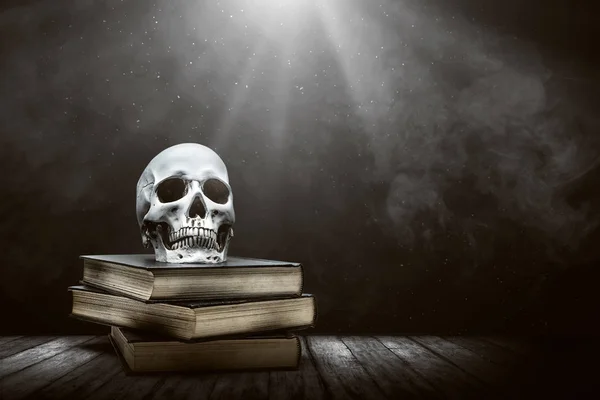 Pilha do livro com um crânio humano em uma mesa de madeira — Fotografia de Stock