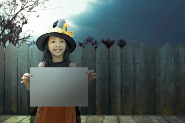 Азиатская маленькая девочка в костюме ведьмы держит вывеску для копа — стоковое фото