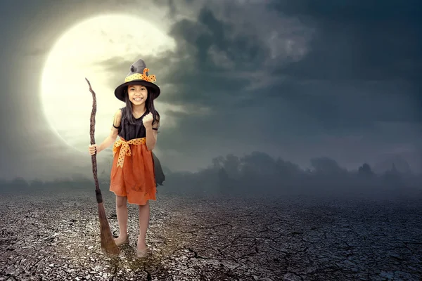 Asiática bruja chica con la magia escoba en el agrietado suelo — Foto de Stock