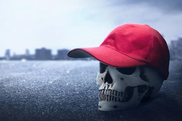 Ludzka czaszka w czerwonym kapeluszu na miejskiej ulicy — Zdjęcie stockowe
