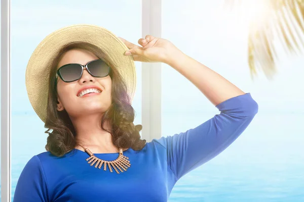 ビーチを背景にリゾートに立って帽子とサングラスを持つアジアの女性 — ストック写真