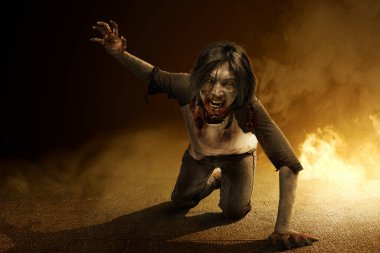 Vücudunda kan ve yara olan korkunç bir zombi yerde sürünüyor.