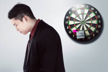 Asyalı işadamı hedef metniyle depresyona girmiş hissediyor. Duvardaki dartta başarısız oldu.