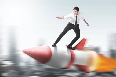 Bulanık arka planı olan bir roketin üzerinde uçan Asyalı işadamı