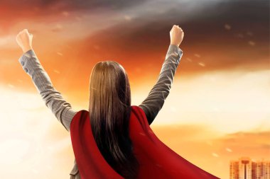 Gökyüzünde süper kahraman gibi uçan bir pelerinli Asyalı iş kadını.