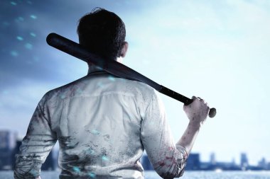 Asyalı bir adam elinde beyzbol sopasıyla şehirde duruyor.