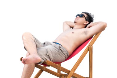 Plaj sandalyesinde uzanan güneş gözlüklü Asyalı adam beyaz arka planda izole edilmiş.