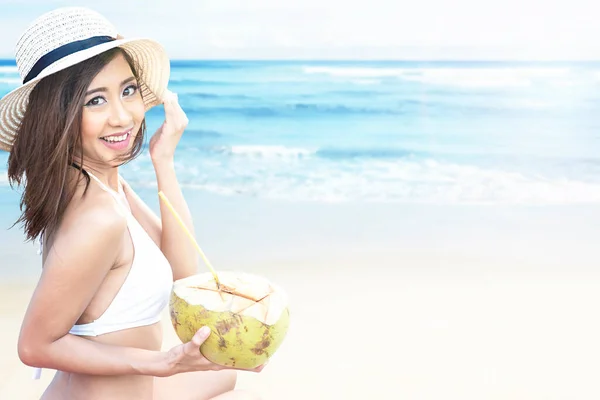 亚洲女人 戴着比基尼和帽子 在海滩上拿着椰子水果 — 图库照片