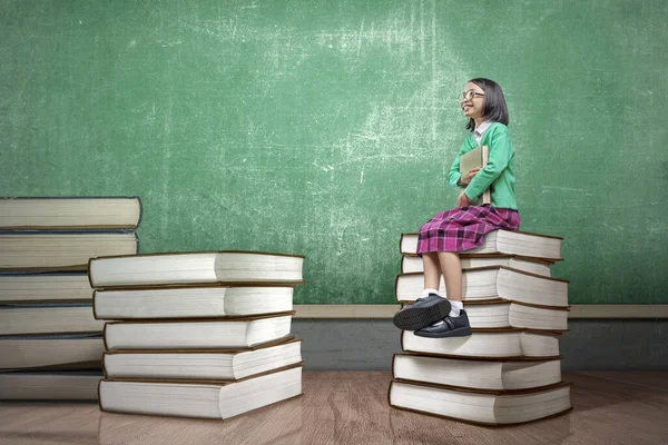 一个戴眼镜的亚洲小女孩坐在书架上 回到学校的概念 — 图库照片