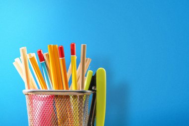 Kırtasiye sepetinde mavi arka planlı kalem ve zımba. Okul konseptine dönüş