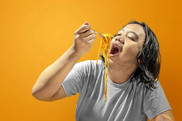 Asiatisk Man Äter Spaghetti Med Färgad Bakgrund Skräpmat Koncept — Stockfoto