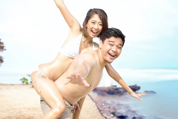亚洲男人穿着比基尼在海滩上抱着他的女朋友 — 图库照片