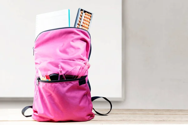 Rucksack Mit Buch Und Schreibwaren Auf Holztisch Mit Whiteboard Hintergrund — Stockfoto