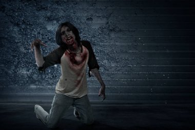 Vücudunda kan ve yara olan korkunç zombi grunge duvar arka planıyla sürünüyor.