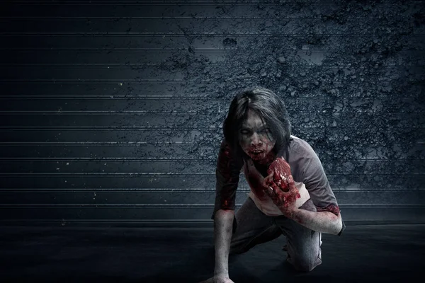 可怕的僵尸身上有血和伤痕 吃着墙背景的生肉 — 图库照片