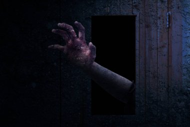 Kapıdaki bir delikten çıkan bir zombi eli.