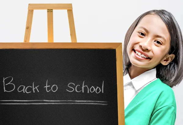 Sınıfın içindeki tahta sehpada küçük bir karatahta duran Asyalı küçük kız. Okula geri dön.