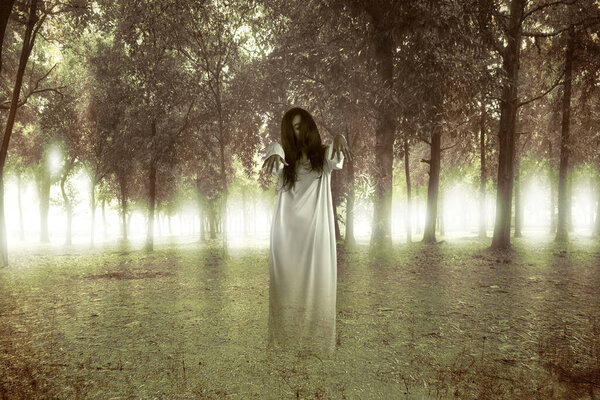 Scary ghost woman standing with haunted forest background. Halloween concept