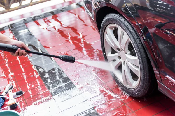 Garajda arabanın tekerleklerini temizleyen adam.