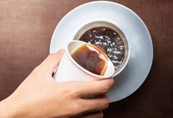 テーブルの上のマグカップに発泡スチロールカップからコーヒーを注ぐ手 国際コーヒーの日 — ストック写真
