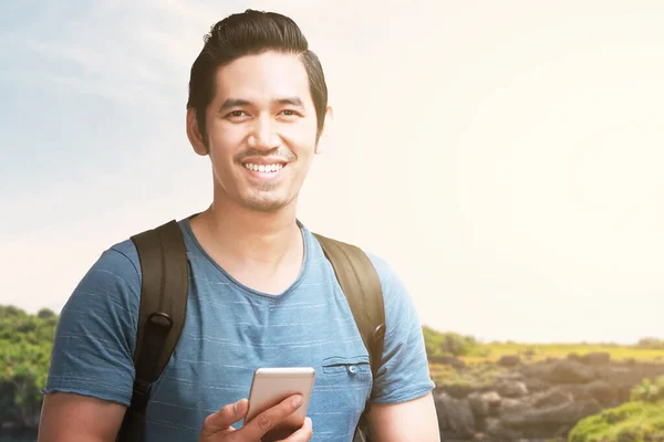 가방을 아시아 남자가 호숫가 풍경과 배경으로 스마트폰을 있습니다 관광의 — 스톡 사진