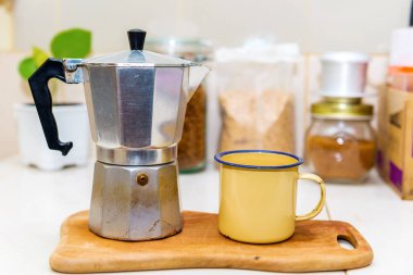 Eski kahve makinesi ve bardak masanın üstünde.