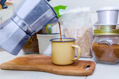 Kahve makinesinden bardak fincanına kadar kahve dolduruyorum.