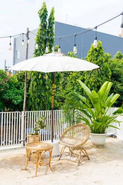 Terastaki masa ve sandalye yeşil bitkilerle dolu.