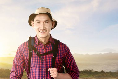 Manzara manzaralı, mavi gökyüzü arka planlı, sırt çantalı Asyalı bir adam. Dünya Turizm Günü