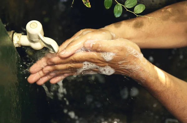 Man washing his hands with soap and running water at outdoor