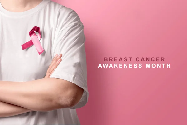 Woman in a white shirt showing a pink awareness ribbon. Breast cancer awareness